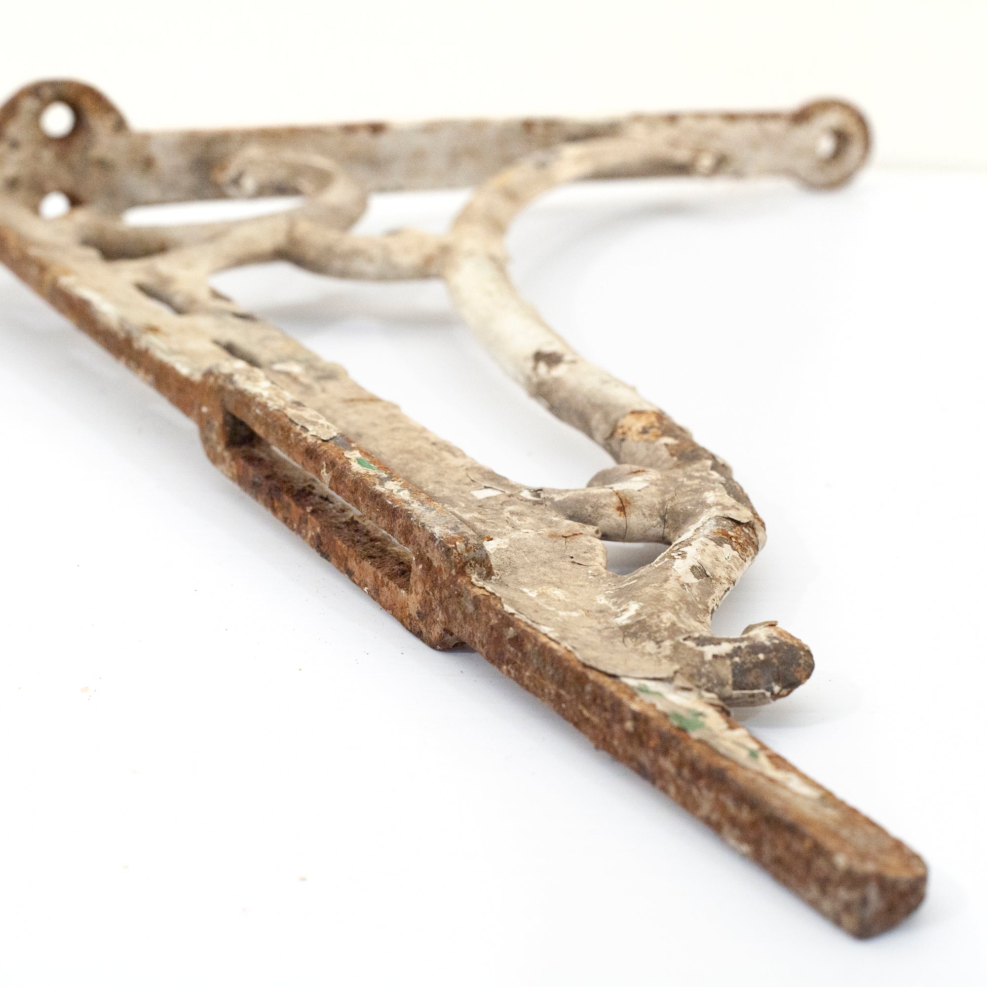 this picture shows the top angle of a vintage cast iron shelf bracket where you can see the rust on the top