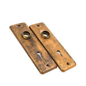 this is a side angle view of a pair of antique vintage victorian copper floral escutcheons