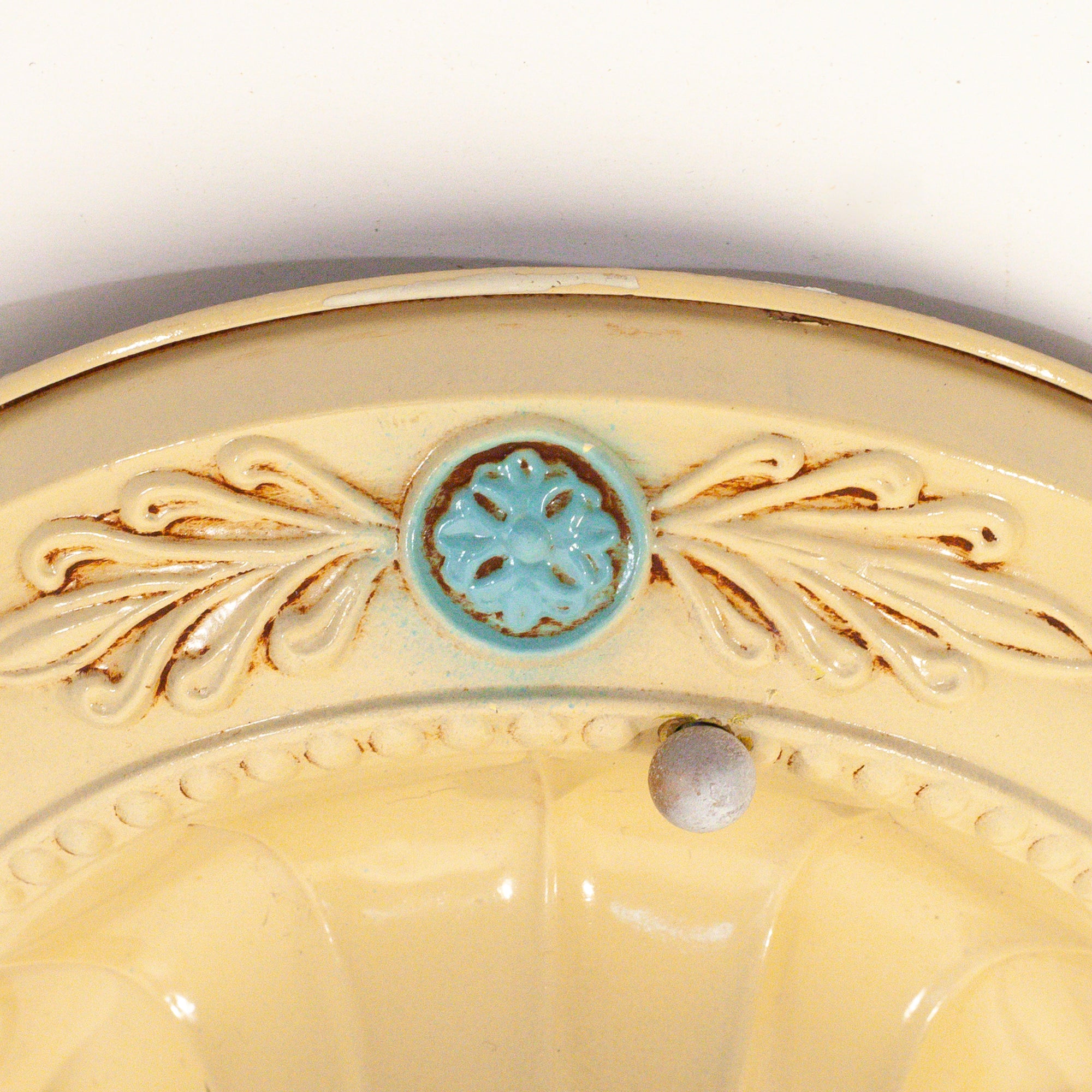 this picture shows the floral detail on the canopy of a vintage bare bulb ceiling fixture. The floral detail in this picture is light blue