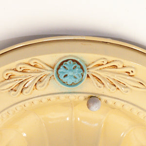 this picture shows the floral detail on the canopy of a vintage bare bulb ceiling fixture. The floral detail in this picture is light blue