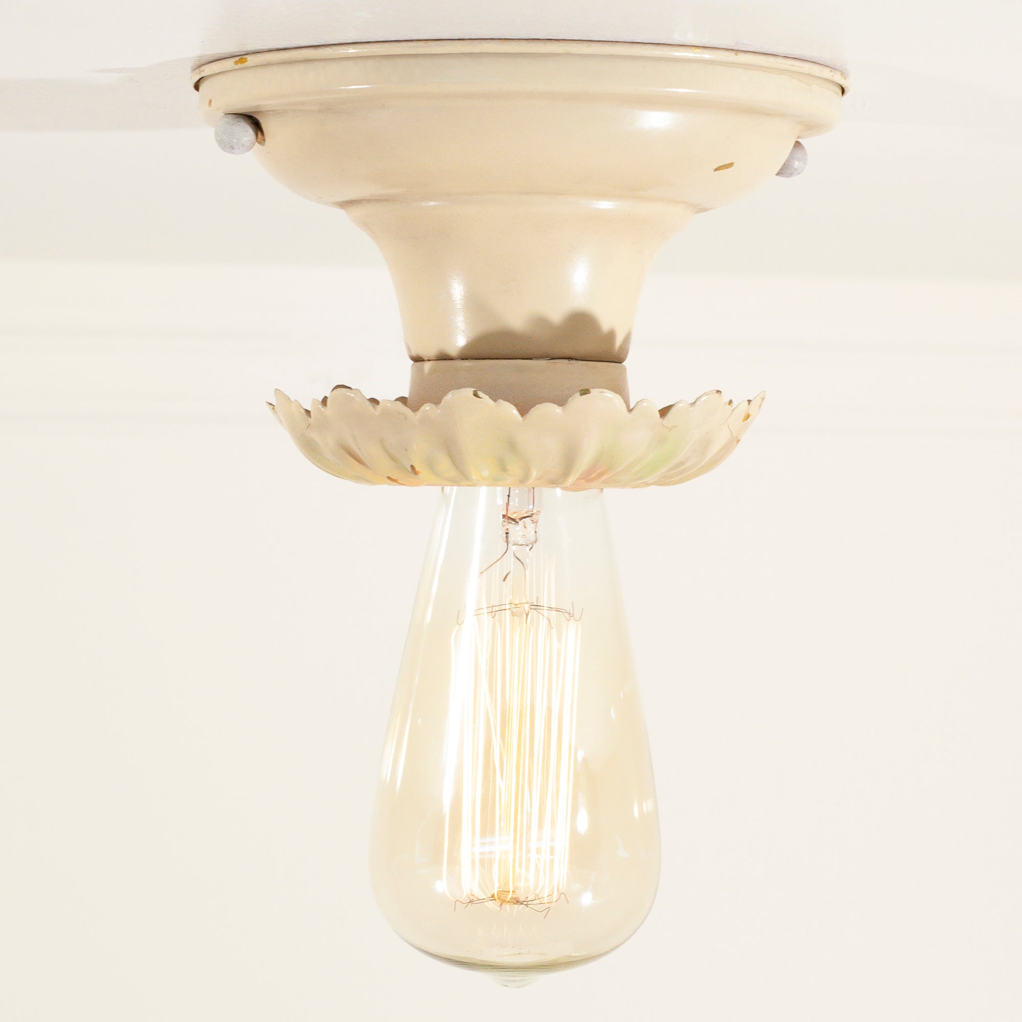 this picture shows an antique vintage bare bulb ceiling fixture with a bulb that is lit up